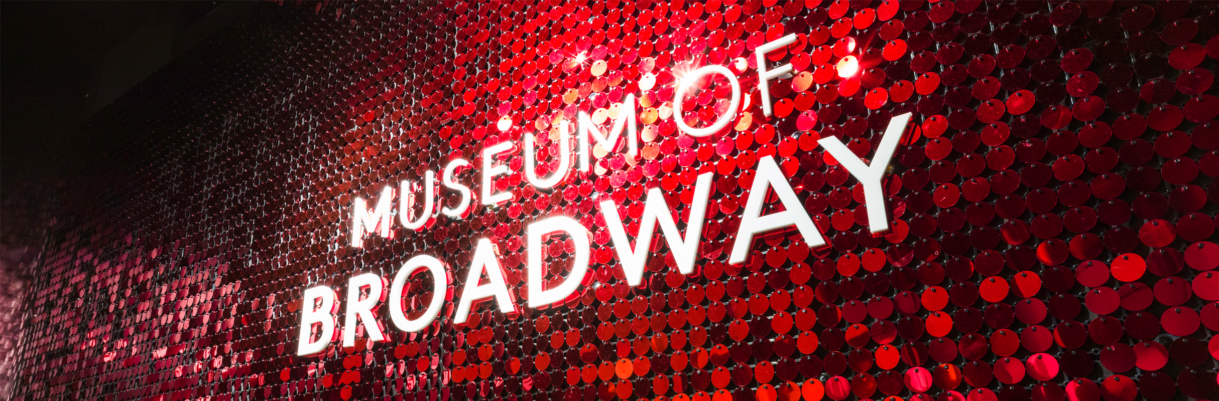 Museum of Broadway logo on red sequin wall.
